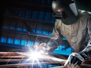 man welding in workshop with safety precaution