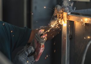 A confident man performing a welding task, with sparks flying all around him as a result