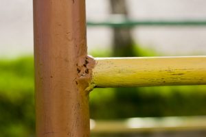 Detail of old construction made of painted welted metallic pipes, fence, ladder or gate on bright sunny outdoors background.